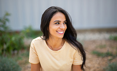 Smiling woman outdoors looking to the side, conveying happiness and a relaxed, positive mood.