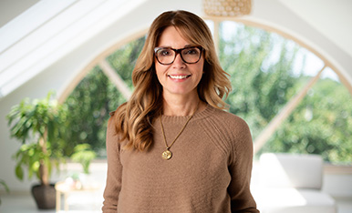 Smiling woman wearing glasses in a bright office, likely staff profile or introduction image.