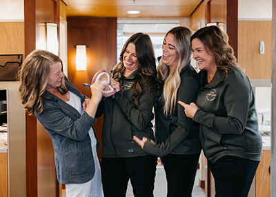 our dental team members smile and examine a dental model together, conveying collaboration and a friendly practice environment.