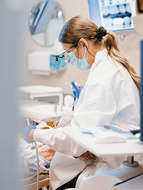 Our StillwaterDentist in mask and loupes performs a procedure on a patient, highlighting focused clinical care.