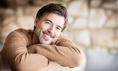 Man smiling with arms rested on the back of a chair